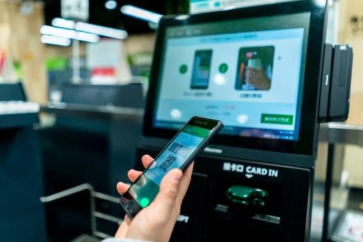 Person holding a phone in front of a monitor