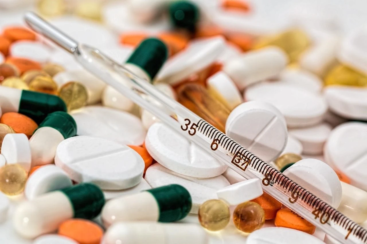 A thermometer on top of a pile of pills