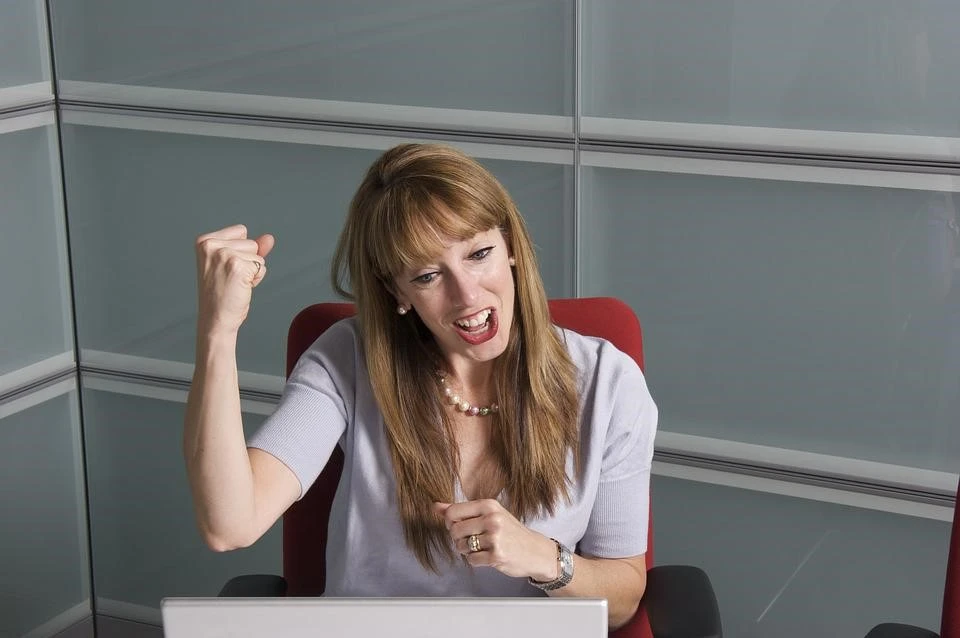 Woman holding a fist in front of a computer