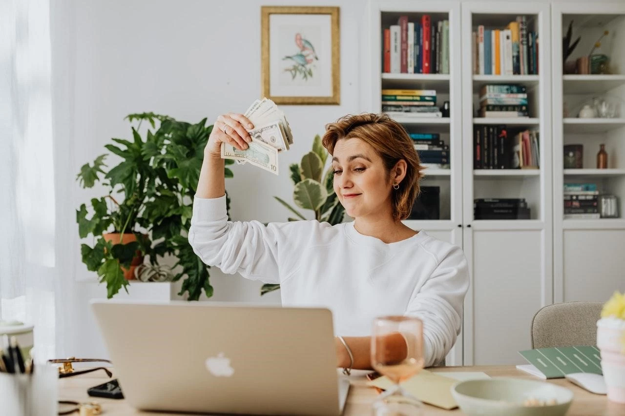 Woman with cash in hand in front of a desk