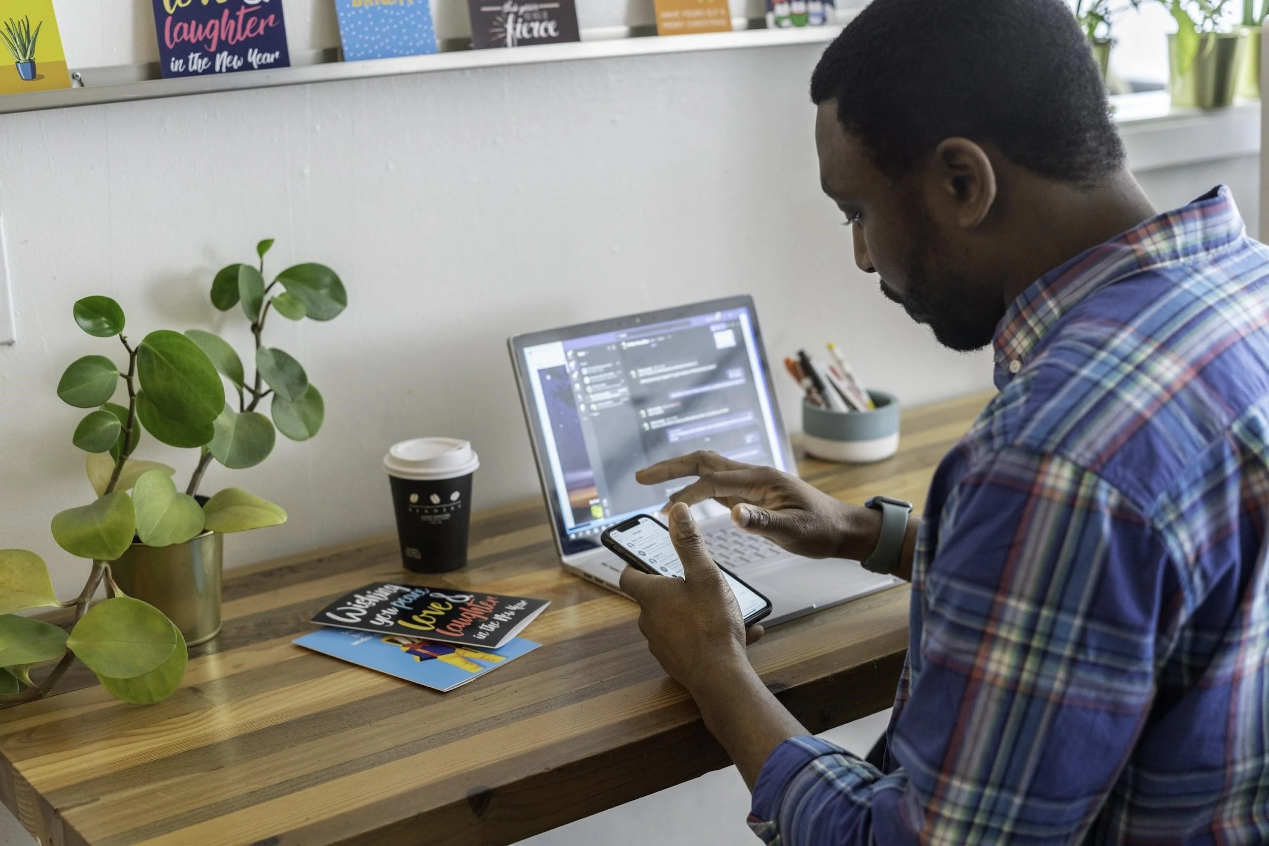 Person with a phone in front of a laptop