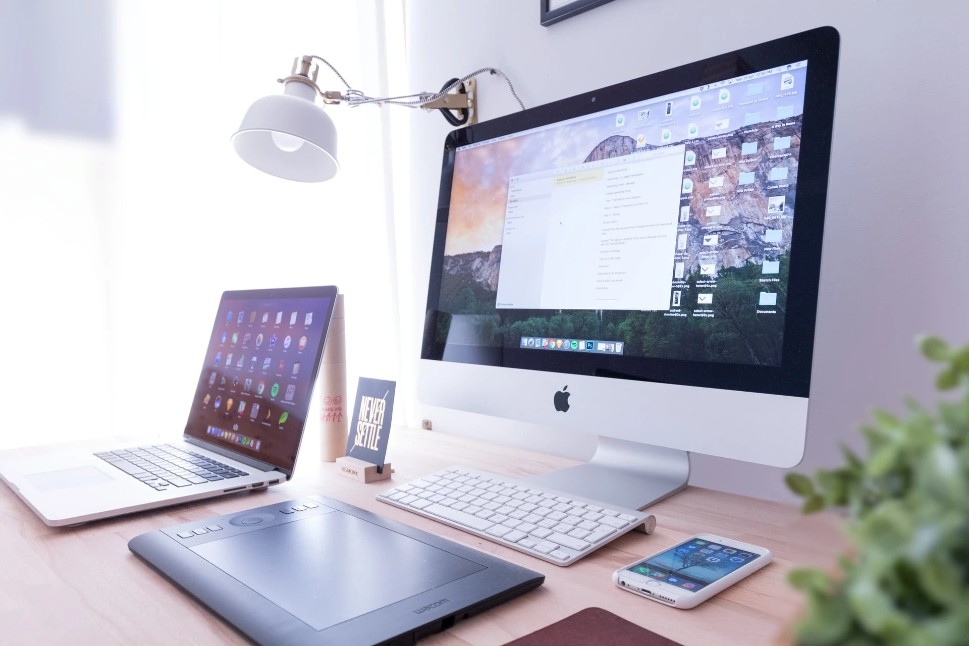 A desk with a Mac, a laptop, and a phone