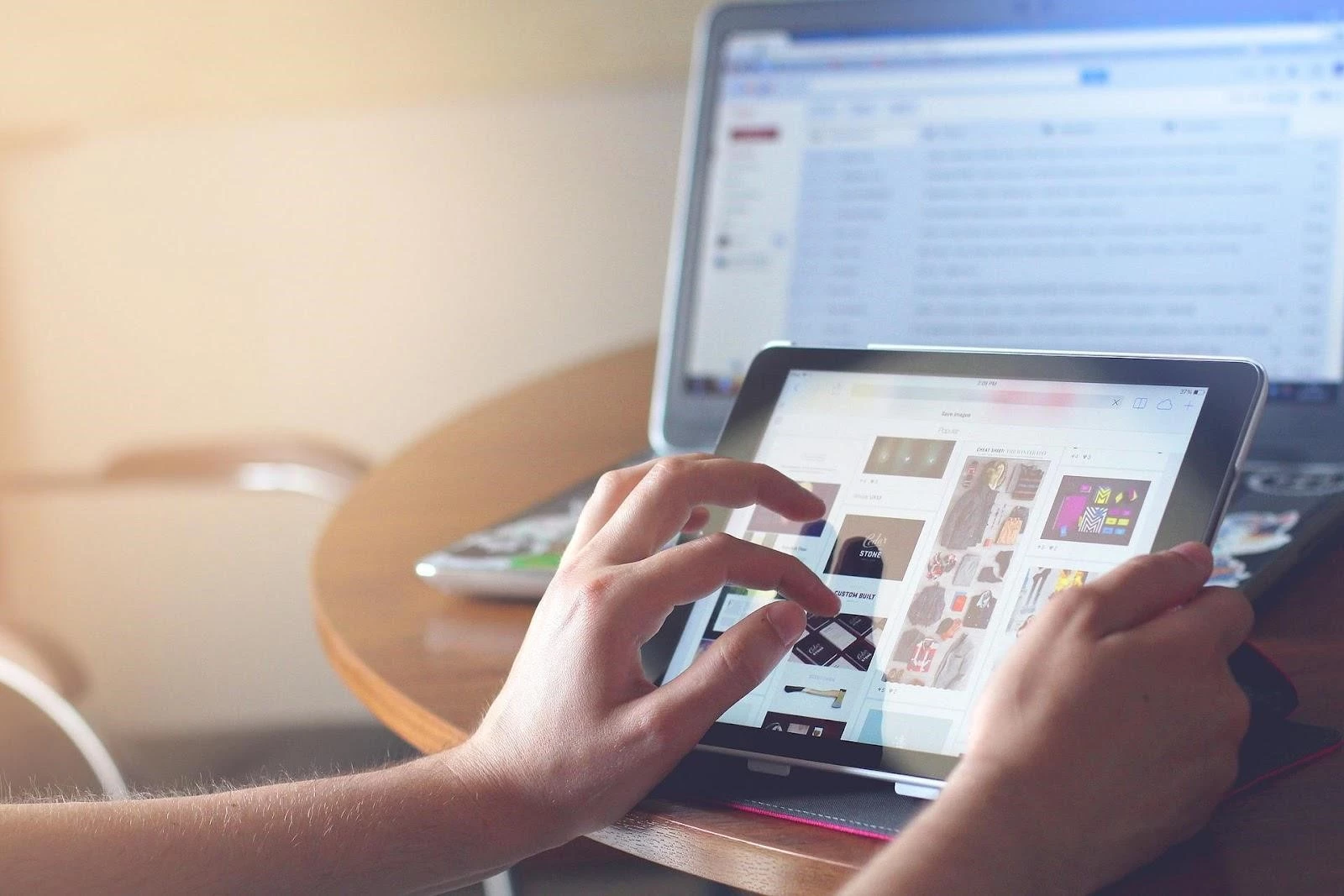 Person using a tablet in front of a laptop