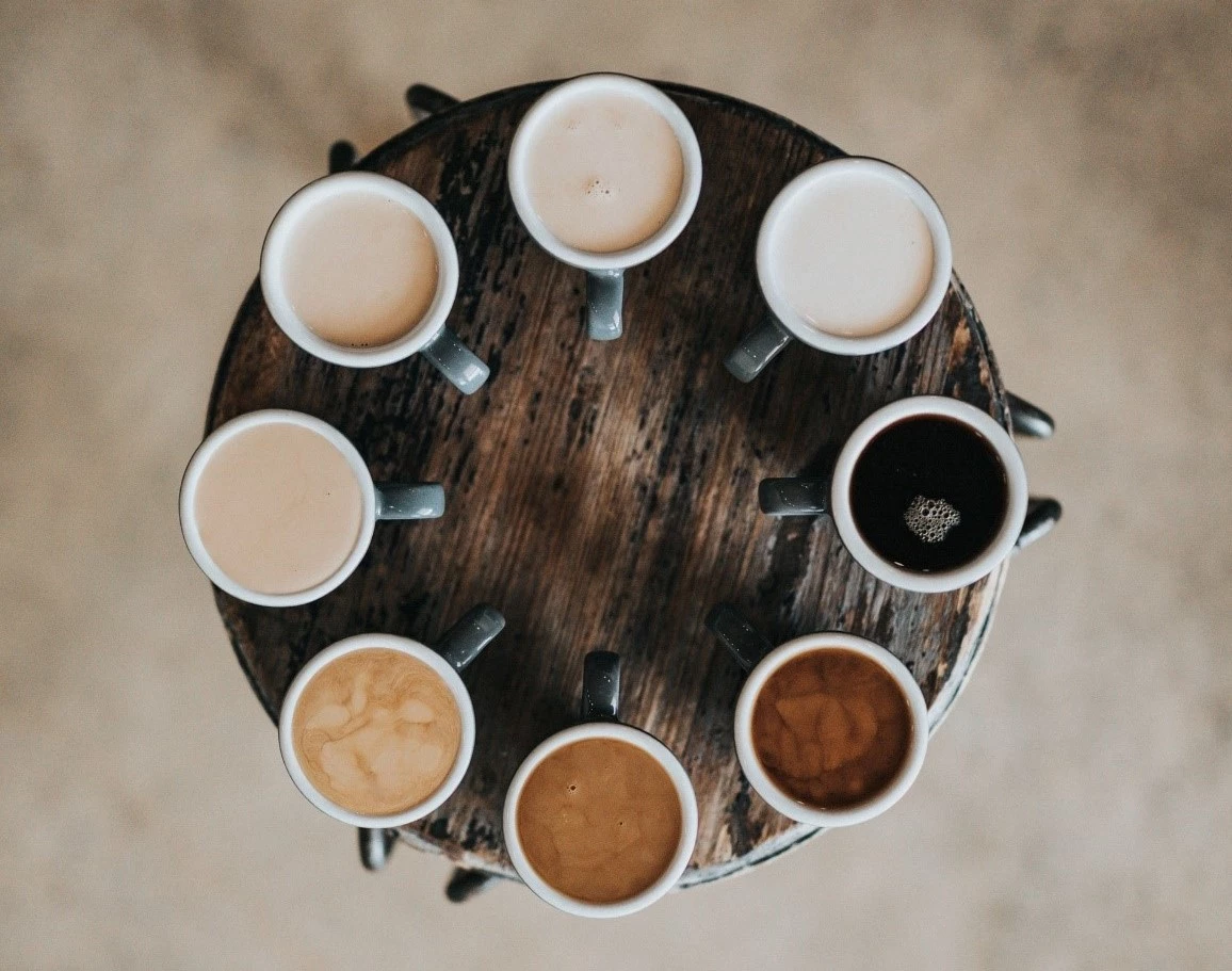 Cups of coffee from light to dark around a table